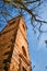 Ruins of an old abandoned church bell tower made of stone and a dry tree under a blue sky on a sunny day