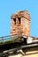 Ruins of old red brick chimney on top of abandoned building with metal roof and rusted edge surrounded with gutter