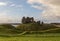 Ruins of an old stone castle on a grassy hill in front of a large river. Clonmacnoise Abbey in Ireland facing the Shannon River