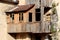 Ruins of wooden house addon with destroyed boards and missing glass on windows and with rusted roof waiting to be demolished and