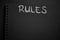 Rules word written on a notepad with blank space. Blank black notepad background