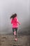 Run fit woman runner running on trail path in mountains in fog and clouds - morning jogging training in pink sportswear