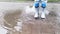 Run through puddle in rubber boots and enjoy wet spring weather like little child. Video of legs without persons face.