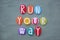 Run your way, creative slogan composed with multi colored stone letters over green sand