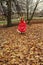The runaway bride the girl in a red dress runs along the fallen autumn leaves before the storm