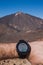 Runner checking progress on smart watch. Volcano on background