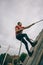 Runner climbing wall with a rope in test of extreme obstacle race