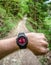 Runner on forest trail looking at wearable sportwatch