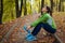 Runner having rest after workout in autumn park. Tired woman holding water bottle. Sportive active lifestyle