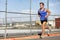 Runner man running - urban city lifestyle. Young sports male athlete jogging in grunge fence background outdoors in summer