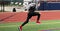 Runner resistance training pulling a sled with weights across a turf field