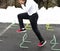 Runner running over mini hurdle in parking lot with snow in background