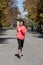 Runner sport woman in Autumn sportswear running and training on jogging outdoors workout in city park smiling happy