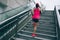 Runner sportswoman climbing up city stairs