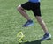 Runner stepping over yellow mini hurdles on a turf field