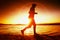 Runner in Sun rays on beach. Sportsman in baseball cap, jogging during the sunrise above sea