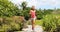 Runner woman running on park path exercising on beautiful summer day