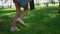 Running children legs on green grass meadow. Unknown kids play jogging outdoors.