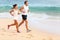 Running couple jogging on beach exercising sport