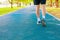 Running feet male in runner jogging exercise with old shoes for health lose weight concept on track rubber cover blue public park