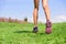 Running girl runner jogging on grass on trail run in summer park . Athlete legs and shoes jumping from behind, heels and