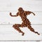 A running man assembled from roasted coffee beans on a white wooden surface