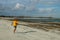 Running man jogging on beach. Indonesian teenager in shorts and a yellow T-shirt running along the beach. Young athlete trains by