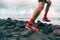 Running shoes of athlete man jogging on beach. Difficult terrain with wet rocks for training outdoors. Runner exercising