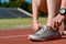 Running shoes closeup, female runner athlete tying laces for training and jogging on stadium track, sport and fitness