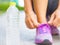 Running shoes - closeup of water bottle and woman tying shoe laces.