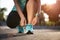 Running shoes - closeup of woman tying shoe laces. Female sport fitness runner getting ready for jogging in garden background