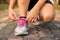 Running shoes - woman tying shoe laces. Closeup of female sport fitness runner getting ready for jogging outdoors on forest.