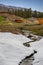 Running stream through snow cover grass meadow in front of a farm cottage