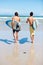 Running, surfing and rear view of men friends at a beach with freedom, energy or fun. Back, fitness and surfer people at