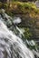 Running water cascade waterfall streaming splashes, decorative granite stonewall background, green moss, grey rock stone wall