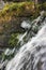 Running water cascade waterfall streaming splashes, decorative granite stonewall background, green moss, grey rock stone wall