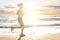 Running woman on sea beach, motion. Girl jogging on sea coast in summer sunny morning. Fitness. Healthy lifestyle