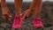 Running woman tying shoe laces going running - girl trail runner. Closeup of female legs and running shoes in action