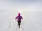 Running woman on winter trail, snow and white mountains