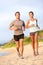 Running young couple jogging in beach sand happy