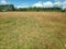 Rural area meadow amidst rolling hills and cloudy sky