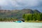 Rural boat floating on waters on background of mountains under the gloomy sky