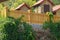 Rural brown wooden fence overgrown with green vegetation