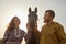 A rural couple with a horse in a natural yellow landscape on an autumn day. Young man and woman together with an animal