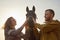 A rural couple with a horse in a natural yellow landscape on an autumn day. Young man and woman together with an animal