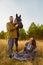 A rural couple with a horse in a natural yellow landscape on an autumn day. Young man and woman together with an animal