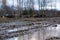 Rural dirt road in late autumn. Off-road, wild dirt trail with large puddles on background of agricultural machinery, tractors,