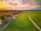 Rural dirt road through spring green fields. Evening countryside scene