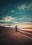 Rural evening scene, vertical photo with a lone nomad man carrying firewood and a bagful on his shoulder, going home walking a