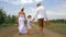 Rural family walking with straw baskets on background of vineyard and apple orchard during harvesting crops, back view